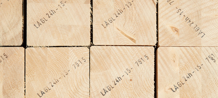 Gestapelte Brettschichtholzbalken mit sichtbarer Jahresringstruktur und Markierungen für den Holzbau.