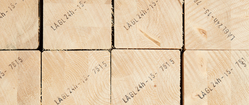 Gestapelte Brettschichtholzbalken mit sichtbarer Jahresringstruktur und Markierungen für den Holzbau.