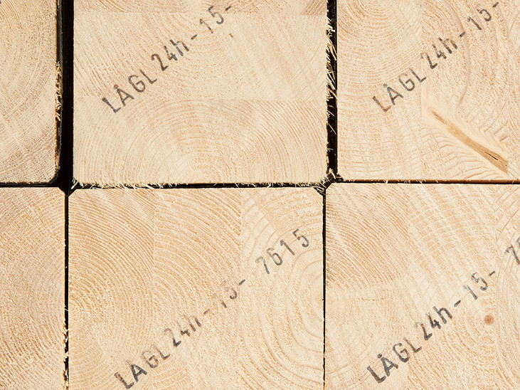 Gestapelte Brettschichtholzbalken mit sichtbarer Jahresringstruktur und Markierungen für den Holzbau.